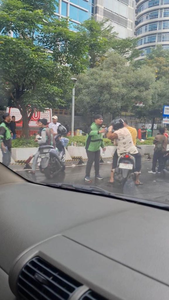 Pemotor membasuh mata di depan Menara Mandiri usai gas air mata dalam kerusuhan Jakarta 2025